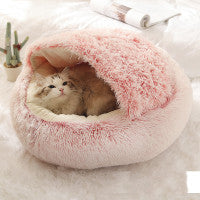 alt= A cat is curled up in a pink, fluffy pet bed that resembles a cozy nest. 